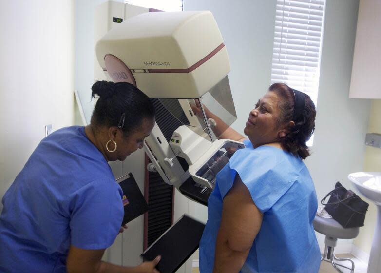FILE - In this May 6, 2010 file photo, detection lead mammographer, Toborcia Bedgood, left, prepares a screen-film mammography test for patient Alicia Maldonado, at The Elizabeth Center for Cancer Detection in Los Angeles. A new, international panel of experts has studied the most recent evidence on mammograms to screen for breast cancer and says they do the most good for women in their 50s and 60s. Women 70 to 74 also benefit to a lesser extent. But evidence that screening helps women in their 40s is "limited," the panel said, although some members disagreed this was true for women 45 to 49. (AP Photo/Damian Dovarganes, File)