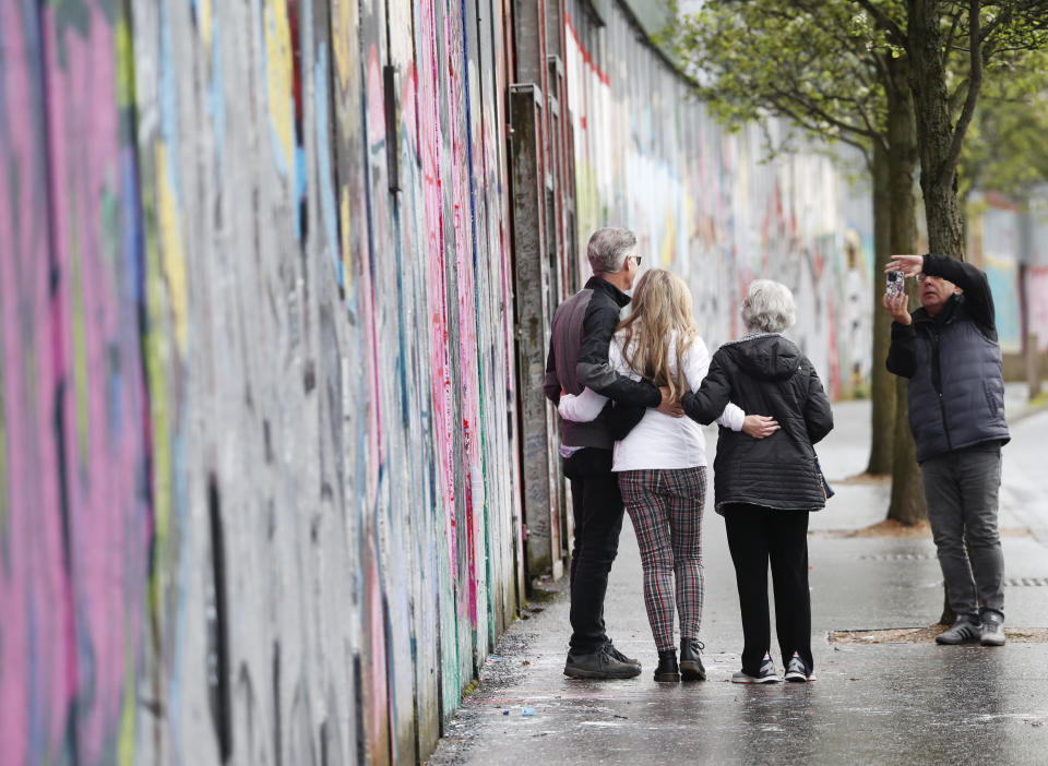 Tourists pose for a photograph next to the “peace walls” that still separate some nationalist and unionist neighborhoods in west Belfast, Northern Ireland, Wednesday, April 5, 2023. It has been 25 years since the Good Friday Agreement largely ended a conflict in Northern Ireland that left 3,600 people dead. (AP Photo/Peter Morrison)