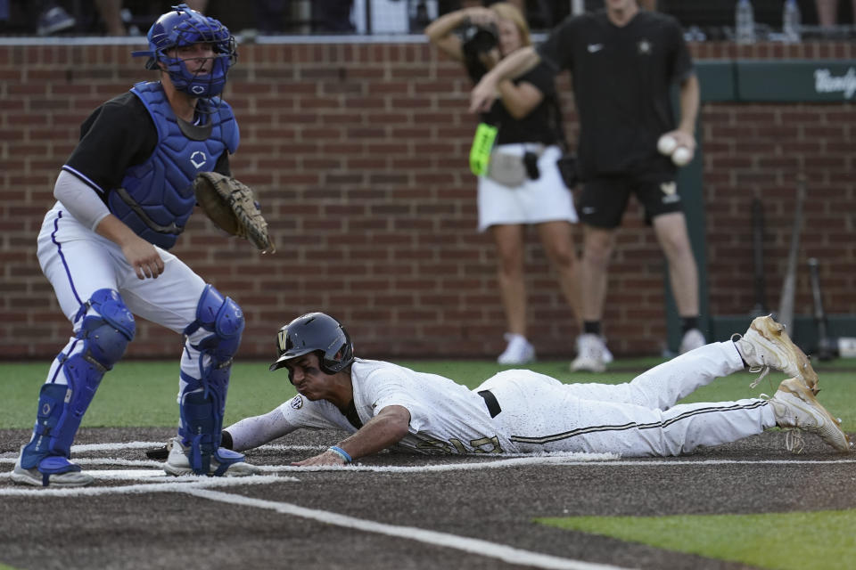 Vanderbilt's Davis Diaz, right, slides past Eastern Illinois Grant Lashure to score a run during the first inning of an NCAA college baseball tournament regional game Friday, June 2, 2023, in Nashville, Tenn. (AP Photo/George Walker IV)