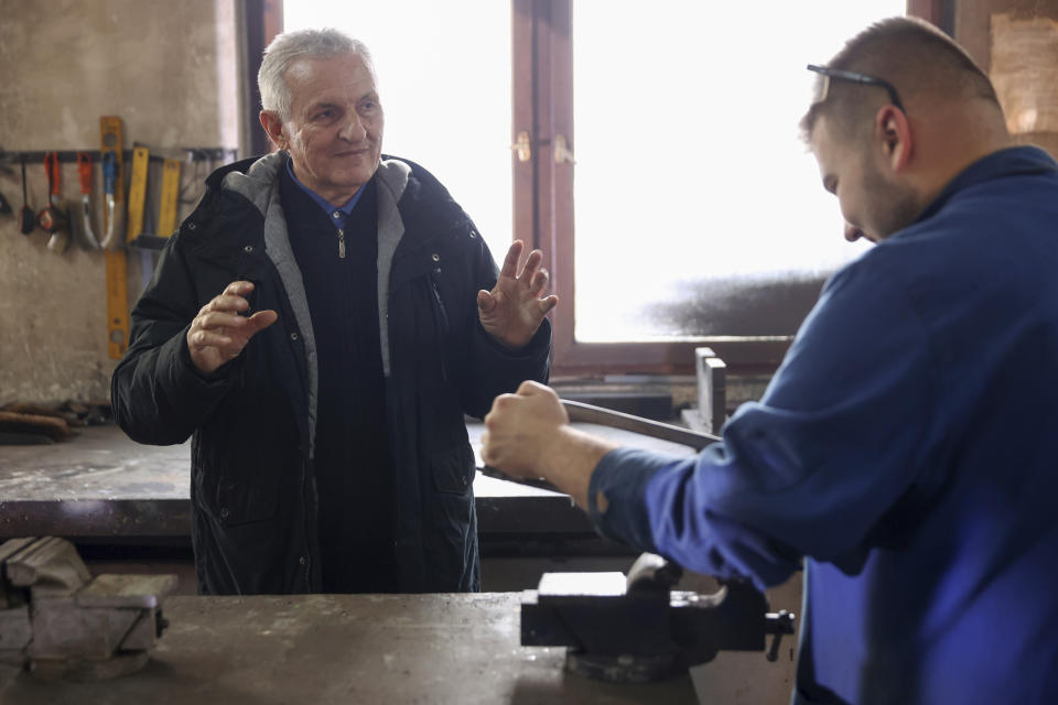 Wartime inventor, engineer and former teacher Aziz Lepenica, left, instructs a student inside a high school workshop in Gorazde, Bosnia, Monday, Dec. 19, 2022. To survive and keep the lights on in their besieged town - cut off throughout Bosnia's 1992-95 interethnic war from access to electricity grid, food, medicine and the outside world - the people of Gorazde had to come up with various creative inventions. (AP Photo/Armin Durgut)