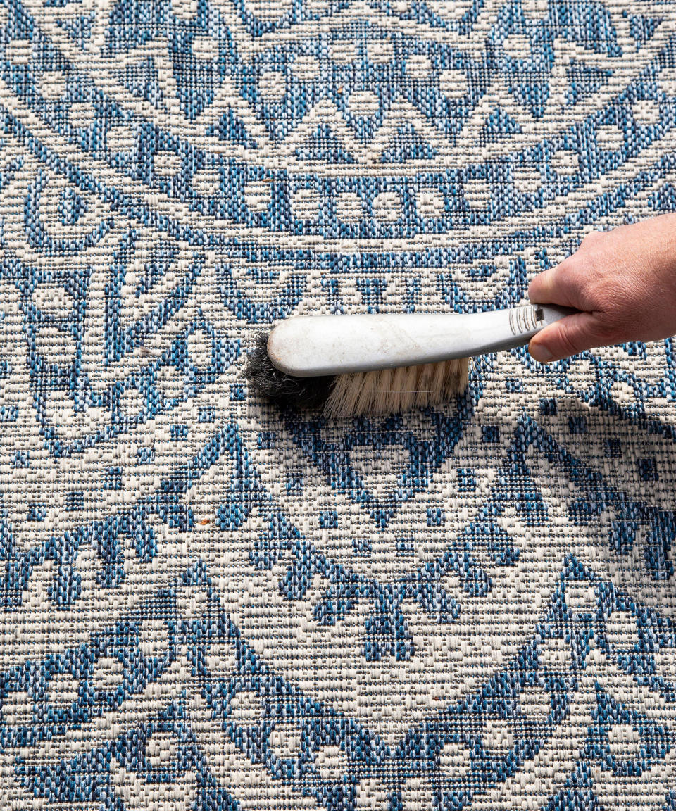 sweeping up dirt from an outdoor rug