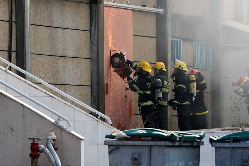 Israeli firefighters use a disc cutter as they work to extinguish a fire in a factory in Sderot, southern Israel