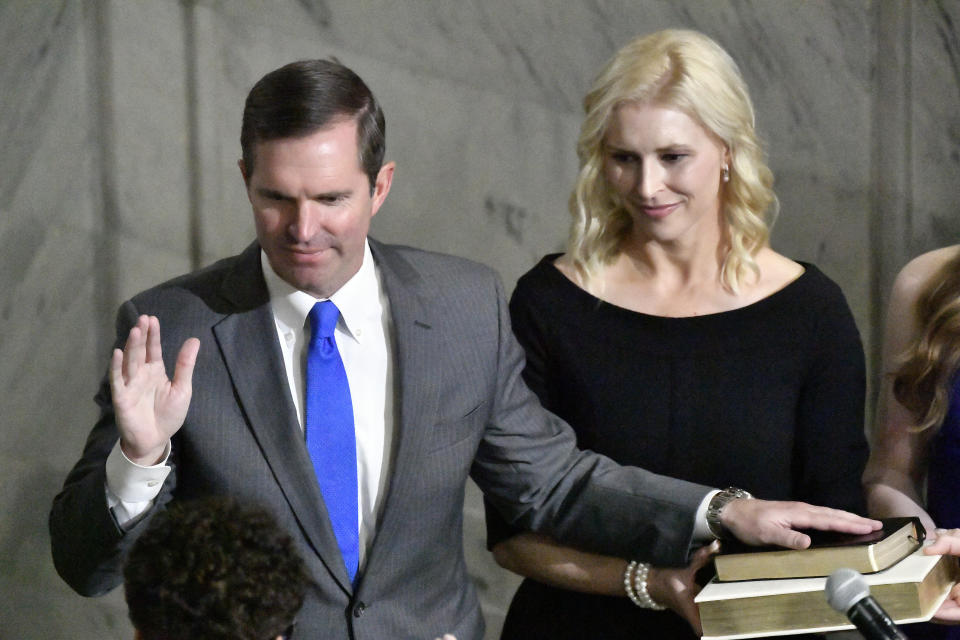 As his wife, Britainy Beshear, holds the Bible, Kentucky Gov. Andy Beshear takes the oath of office from Kentucky Court of Appeals Judge Pamela Goodwine during the 62nd inauguration of Governor in Frankfort, Ky., early Tuesday, Dec. 12, 2023. (AP Photo/Timothy D. Easley)