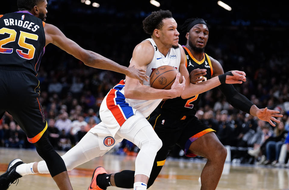 Detroit Pistons' Kevin Knox II (20) drives to the basket between Phoenix Suns' Mikal Bridges (25) and Josh Okogie (2) during the first half of an NBA basketball game in Phoenix, Friday, Nov. 25, 2022. (AP Photo/Darryl Webb)