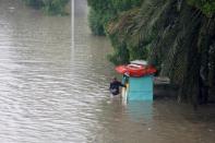 A man stands outside his cabin shop on a flooded street during the monsoon rain, as the outbreak of the coronavirus disease (COVID-19) continues, in Karachi