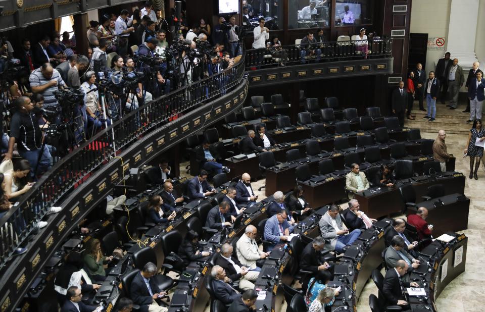 Opposition lawmakers attend a weekly session as the chairs belonging to the pro-government lawmakers stand empty, at the National Assembly in Caracas, Venezuela, Tuesday, Sept 17, 2019. A group of minority opposition parties is entering negotiations with President Nicolas Maduro's government without the consent of the U.S.-backed opposition leader Juan Guaido. (AP Photo/Ariana Cubillos)