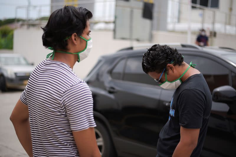 Two men wearing protective face masks wait outside Los Ceibos hospital after Ecuador reported new cases of coronavirus disease (COVID-19), in Guayaquil