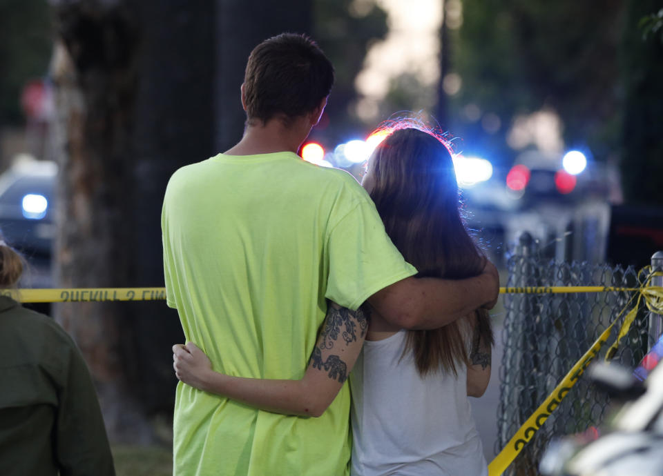 A man and woman watch as law enforcement officers surround a home where a gunman has taken refuge after shooting a Sacramento police officer, Wednesday, June 19, 2019, in Sacramento, Calif. (AP Photo/Rich Pedroncelli)