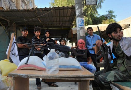 Syrian people stand next to a checkpoint manned by rebels in the northern city of Aleppo. Rebels accused strongman Bashar al-Assad on Tuesday of moving chemical weapons to Syria's borders, a day after his beleaguered regime said it would use its stockpiles if attacked