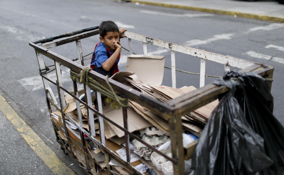 A boy sits in a recycler's cart in Caracas, Venezuela, Saturday, May 4, 2019. (AP Photo/Ariana Cubillos)