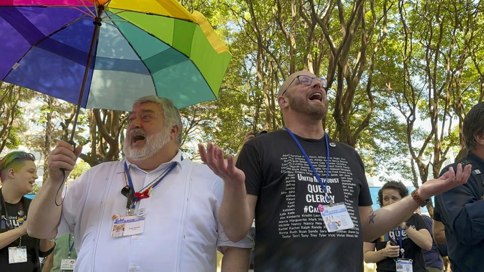 FILE - The Rev. David Meredith, left, and the Rev. Austin Adkinson sing during a gathering of those in the LGBTQ community and their allies outside the Charlotte Convention Center, in Charlotte, N.C., Thursday, May 2, 2024. When the United Methodist Church removed anti-LGBTQ language from its official rules in recent days, it marked the end of a half-century of debates over LGBTQ inclusion in mainline Protestant denominations. The moves sparked joy from progressive delegates, but the UMC faces many of the same challenges as Lutheran, Presbyterian and Episcopal denominations that took similar routes, from schisms to friction with international churches to the long-term aging and shrinking of their memberships. (AP Photo/Peter Smith, File)