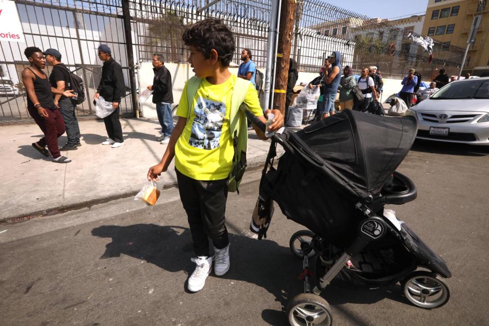 A migrant child, with the Escalona family, stands next his sister's baby carriage while