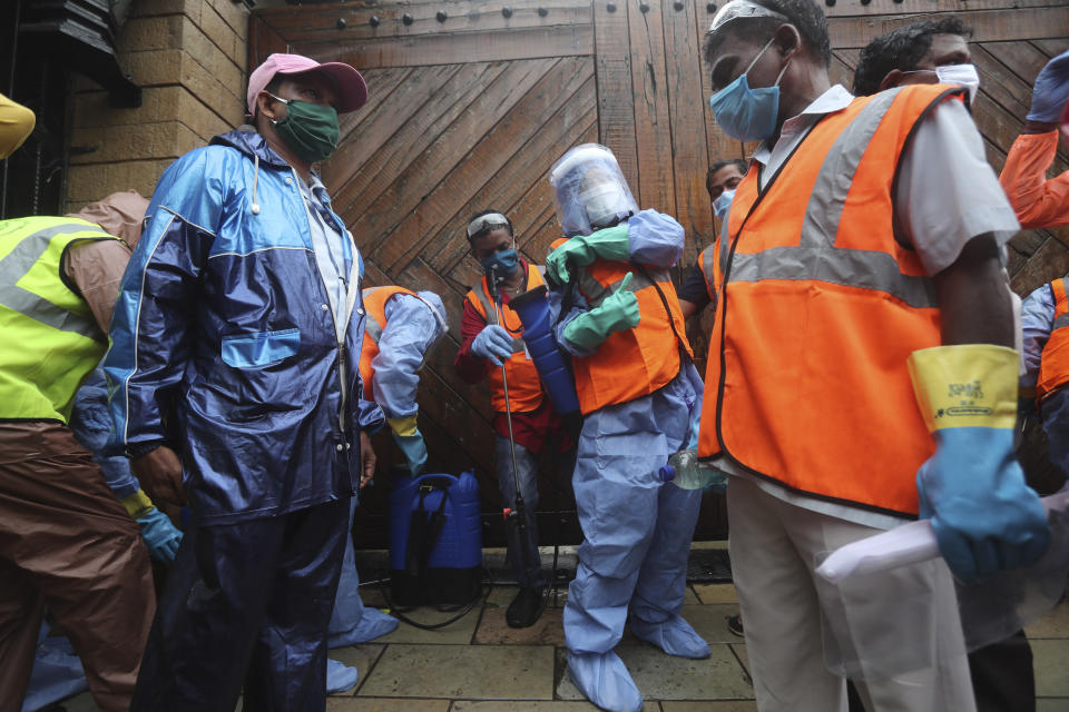 Civic workers wait at the entrance of Bollywood superstar Amitabh Bachchan's residence to sanitize the building after Bachchan and his son tested positive for the coronavirus and were hospitalized in Mumbai, India, Sunday, July 12, 2020. (AP Photo/Rafiq Maqbool)