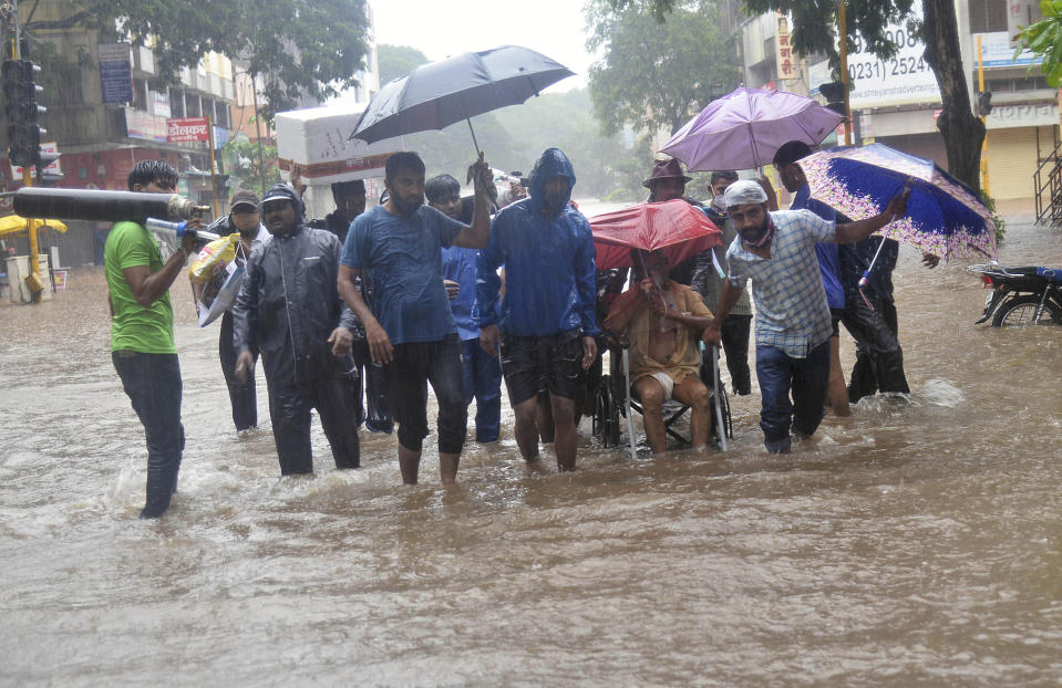 A man wearing an oxygen mask is helped on a wheelchair through floodwaters in Kolhapur, in the western Indian state of Maharashtra, Friday, July 23, 2021. Landslides triggered by heavy monsoon rains hit parts of western India, killing more than 30 people and leading to the overnight rescue of more than 1,000 other people trapped by floodwaters, officials said Friday. (AP Photo)