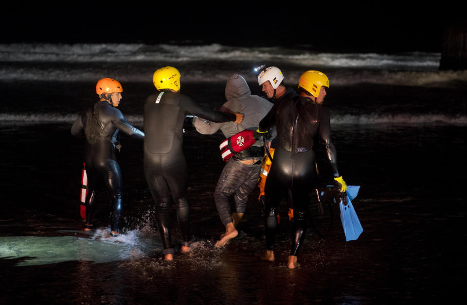 Rescuers hold a Honduran migrant who tried to cross the U.S. border by the sea in Tijuana beach, Mexico, Thursday, Nov. 29, 2018. Aid workers and humanitarian organizations expressed concerns Thursday about the unsanitary conditions at the sports complex in Tijuana where more than 6,000 Central American migrants are packed into a space adequate for half that many people and where lice infestations and respiratory infections are rampant. (AP Photo/Ramon Espinosa)