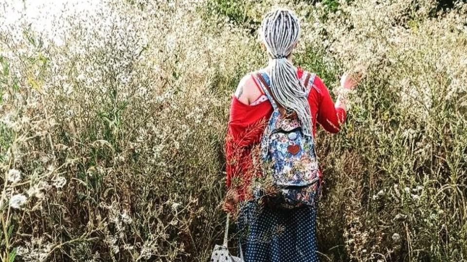 Lia caminando por un campo con flores.