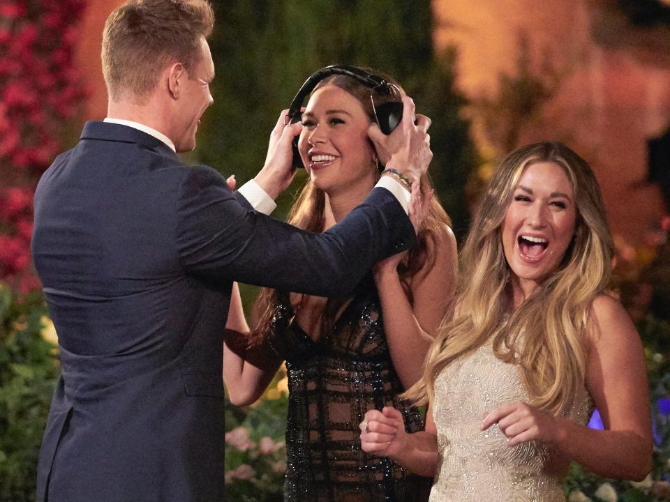 Jordan places a pair of noise-canceling headphones on Gabby Windey while a smiling Rachel Recchia looks on in this still from the season 19 premiere of "The Bachelorette."