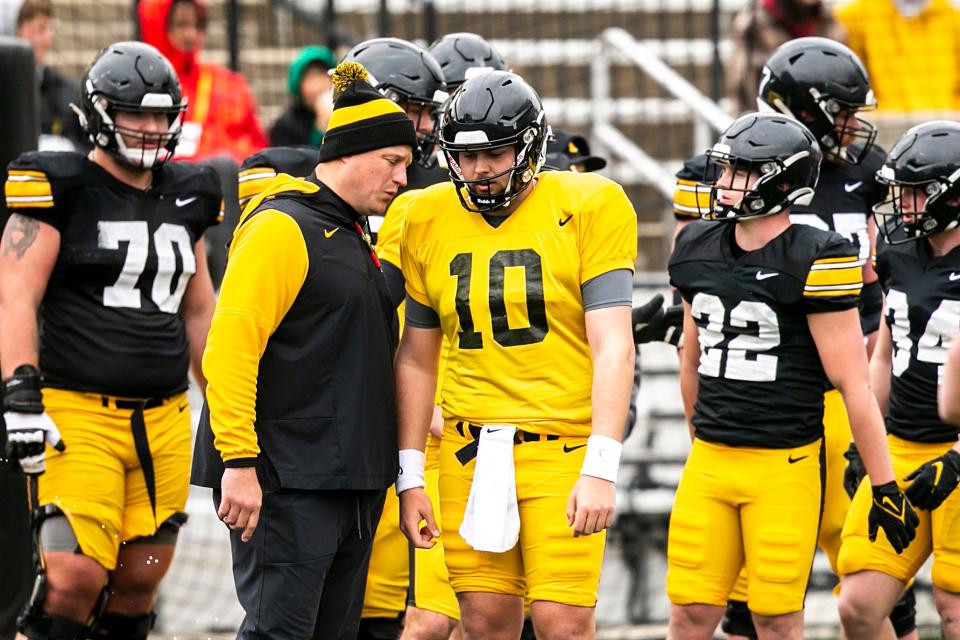 Iowa offensive coordinator and quarterbacks coach Brian Ferentz, second from left, talks with quarterback Deacon Hill (10) during the Hawkeyes' final spring NCAA football practice, Saturday, April 22, 2023, at Kinnick Stadium in Iowa City, Iowa.