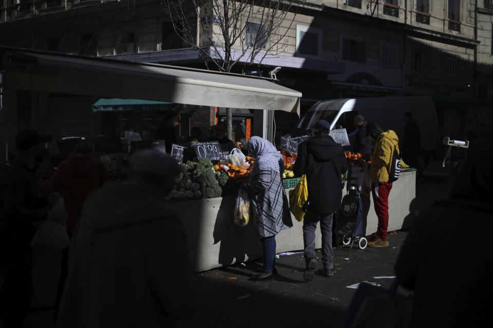 A woman shops at a street market in Marseille, southern France, Wednesday, Feb. 10, 2021. More than three dozen police officers descended on a small private school in Paris, blocked students inside their classrooms, took photos everywhere, even inside the refrigerator, and grilled the school director in her office. The dragnet sweeps schools, shops, clubs or mosques to rout out “radicalization." (AP Photo/Daniel Cole)