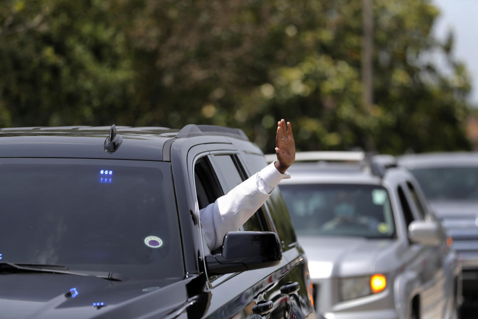 A line of cars with friends and family, who could not attend the funeral for Larry Hammond due to the coronavirus pandemic, pass by his family and their home to pay their respects, in New Orleans, Wednesday, April 22, 2020. Honking, waving and calling to his family, drivers and passengers showed their respect and love for the 2007 king of the Zulu Social Aid and Pleasure Club, a retired postal worker and Air Force veteran who tutored, mentored and provided Christmas presents through Omega Psi Phi. (AP Photo/Gerald Herbert)