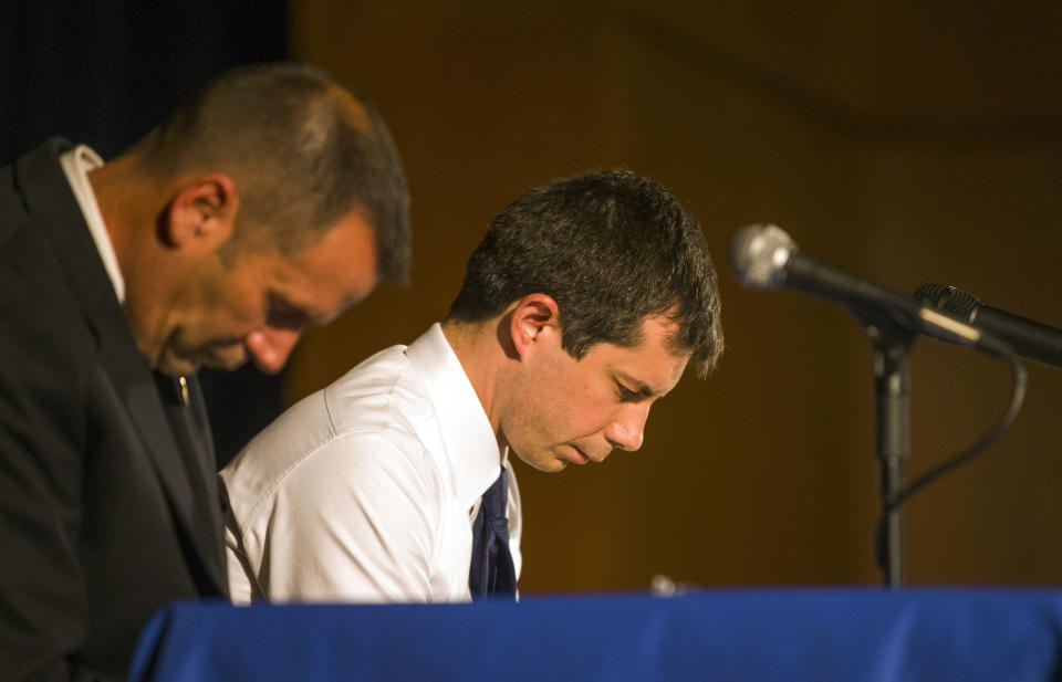 In this June 23, 2019 photo, Democratic presidential candidate and South Bend Mayor Pete Buttigieg, right, and South Bend Police Chief Scott Ruszkowski, left, bow their heads in prayer during a town hall community meeting at Washington High School in South Bend, Ind. Several Democratic White House hopefuls are explicitly connecting their faith to their agendas, making a values-based appeal to religious swing voters who will be critical in next year’s election after white evangelicals broke heavily for President Donald Trump. (Robert Franklin/South Bend Tribune via AP)