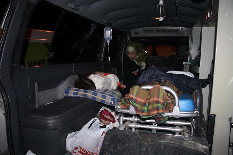 Australia-bound asylum-seekers sit in an ambulance after their boat capsized near Indonesia's Java island on September 28, 2013