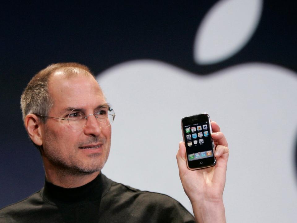 apple cofounder steve jobs holds up an original iphone from 2007