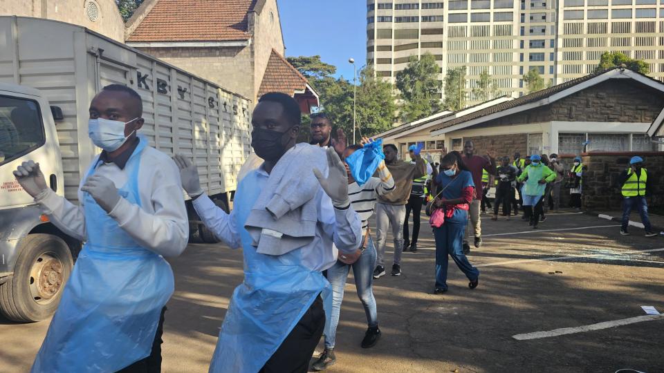 Doctors leave a building with their hands up