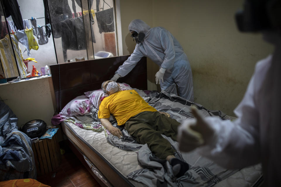 Piedrangel funeral home workers prepare to remove the body of a man suspected to have died from the new coronavirus, from his home in Lima, Peru, Friday May 15, 2020. The workers are part of the Piedrangel funeral team who have been commissioned by the government to remove and cremate the bodies of deceased persons with suspected or confirmed COVID-19. (AP Photo/Rodrigo Abd)