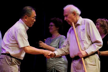 Nobel Laureate Roy Glauber (R) congratulates Atsugi Higashiyama of Japan for winning the 2016 Ig Nobel Prize in Perception for "investigating whether things look different when you bend over and view them between your legs" during the 26th First Annual Ig Nobel Prize ceremony at Harvard University in Cambridge, Massachusetts, U.S. September 22, 2016. REUTERS/Brian Snyder