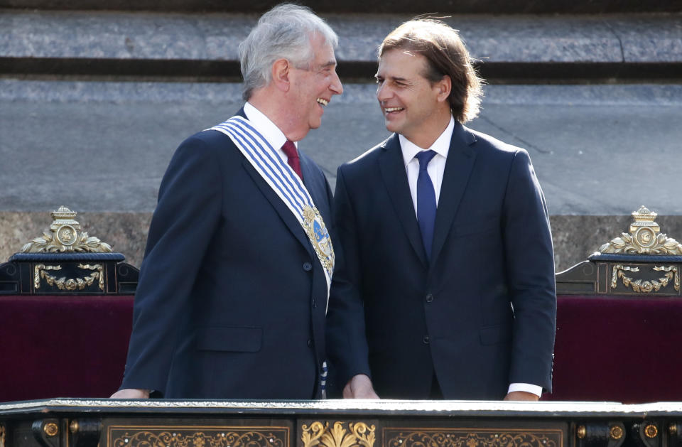 Uruguay's new President Luis Lacalle Pou, right, smiles at outgoing president Tabare Vazquez before receiving the presidential sash in Montevideo, Uruguay, Sunday, March 1, 2020. (AP Photo/Natacha Pisarenko)