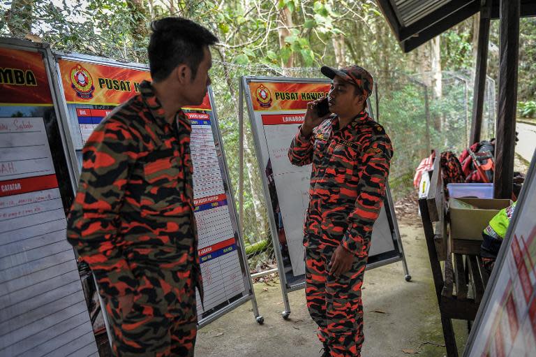 A member of a Malaysian rescue team talks with his mobile phone at the Timpohon gate checkpoint as they wait for victims to be evacuated a day after an earthquake in Kundasang, a town in the district of Ranau on June 6, 2015