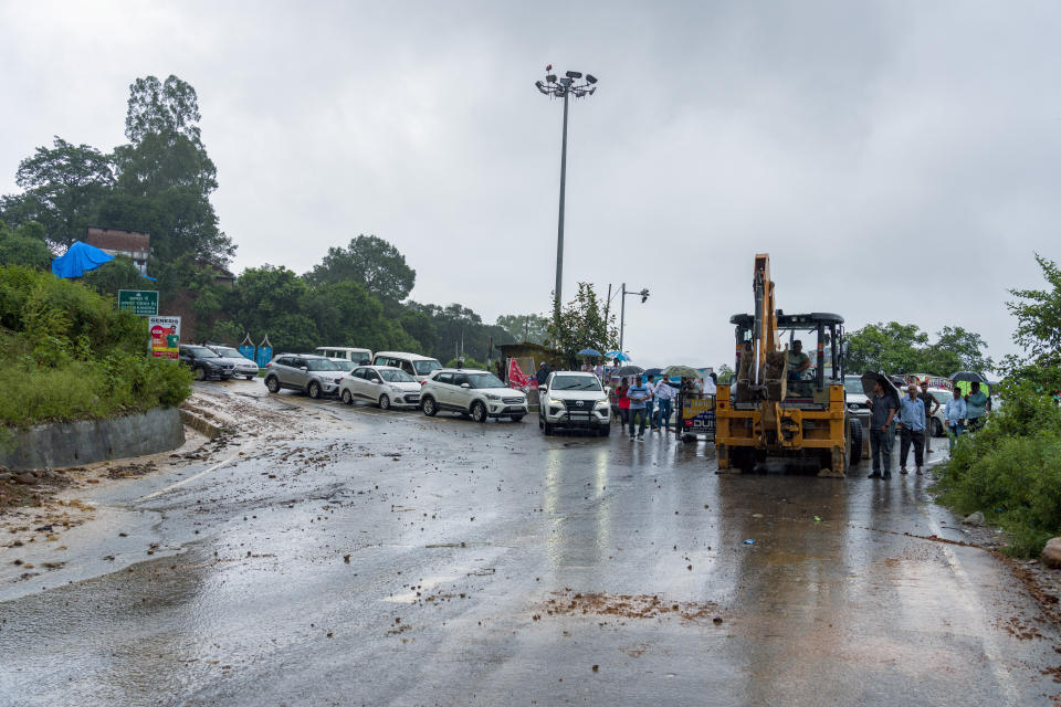 Vehicles wait to cross a part of the road being cleared after a landslide in Kangra, near Dharamshala, India, Monday, Aug. 14, 2023. Heavy monsoon rains triggered floods and landslides in India's Himalayan region, leaving several people dead and many others trapped. (AP Photo/Ashwini Bhatia)