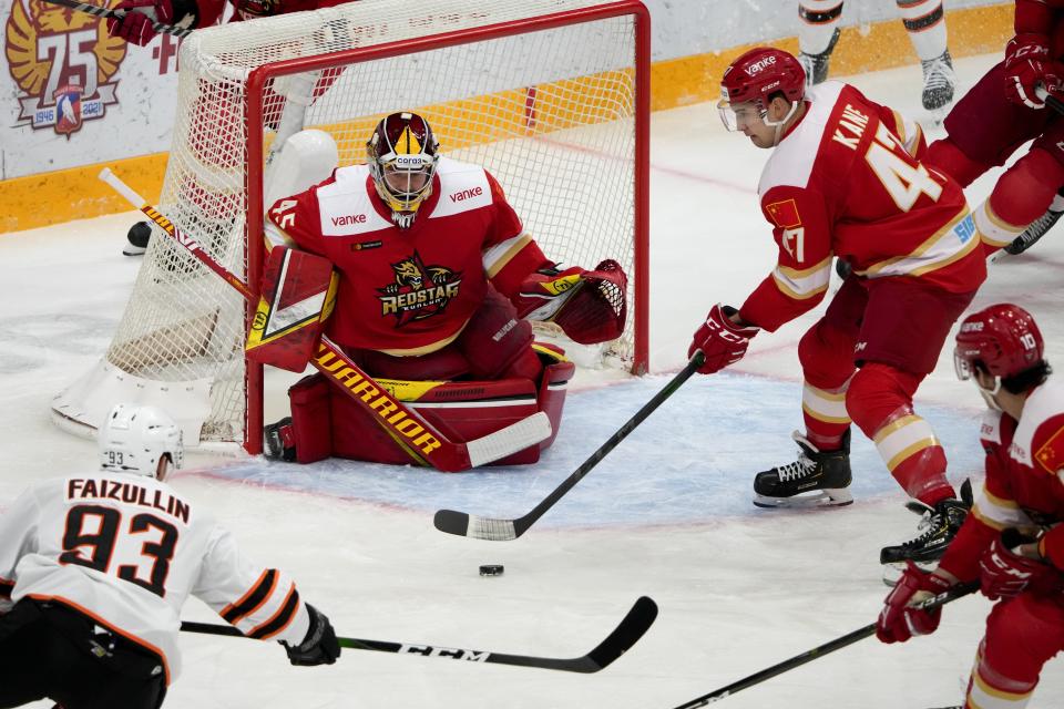 Amur's Danil Faizullin, left, tries to score against Kunlun Red Star's goalie Jeremy Smith, center, as Kunlun Red Star's Cory Kane, right, tries to block during the Kontinental Hockey League ice hockey match between Kunlun Red Star Beijing and Amur Khabarovsk in Mytishchi, just outside Moscow, Russia, Monday, Nov. 15, 2021. Many of Kunlun Red Star's players are aiming to represent the Chinese national team at the Olympics in Beijing. (AP Photo/Alexander Zemlianichenko)