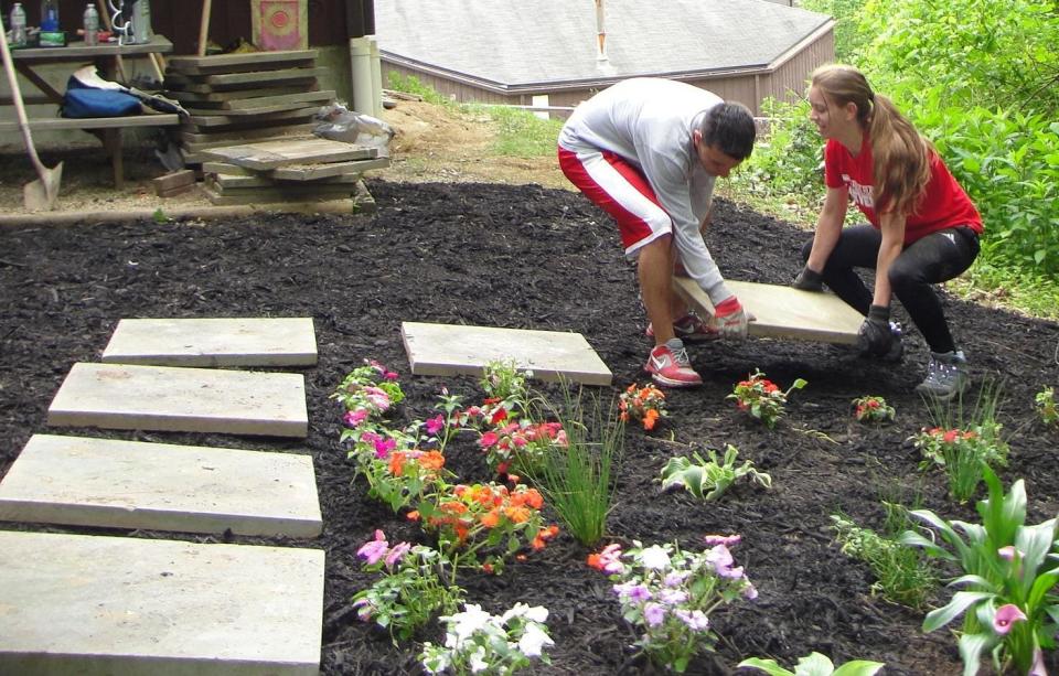 Liam O’Donnell and Shannon Murray create a pathway with pavers as part of restoration work on a garden at Stepping Stones.