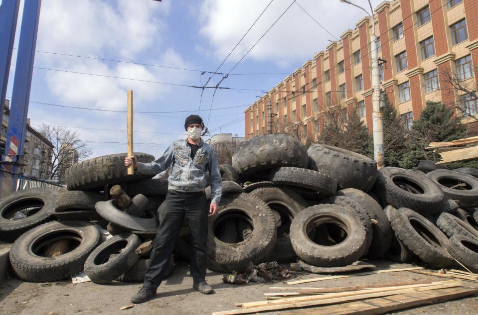 A masked pro-Russian activist poses for a photo in front of barricades at the Ukrainian regional office of the Security Service in Luhansk, 30 kilometers (20 miles) west of the Russian border, in Ukraine, Wednesday, April 9, 2014. Ukrainian Interior Minister Arsen Avakov said the standoff in Luhansk and the two neighboring Russian-leaning regions of Donetsk and Kharkiv must be resolved within two days.(AP Photo/Igor Golovniov)