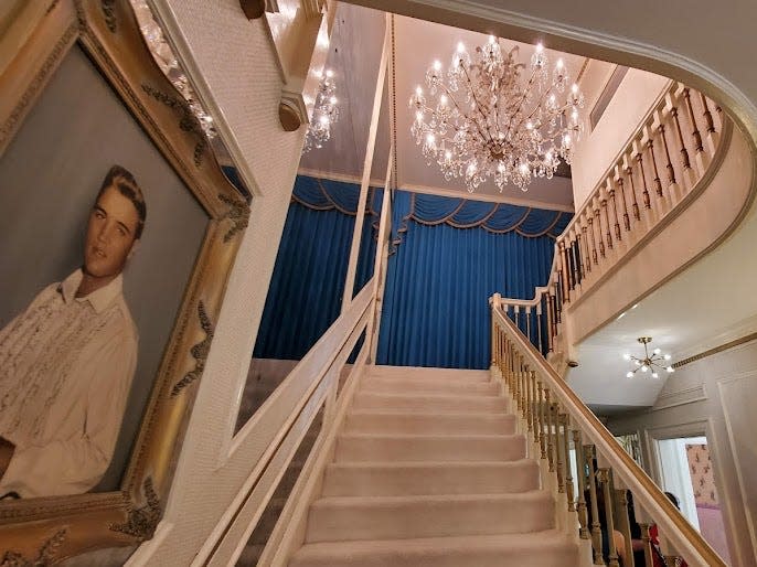 A view of the stairs and chandelier in Graceland, with an Elvis picture