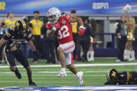 Ohio State running back TreVeyon Henderson (32) runs between Missouri defensive back Dreyden Norwood (12) and defensive back Tre'Vez Johnson (4) during the first half of the Cotton Bowl NCAA college football game Friday, Dec. 29, 2023, in Arlington, Texas. (AP Photo/Richard W. Rodriguez)