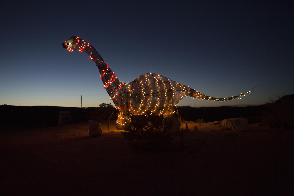 En esta foto del lunes 27 de marzo de 2017, una estatua de un dinosaurio está decorada con luces en Terlingua, Texas, cerca de la frontera con México. (AP Foto/Rodrigo Abd)