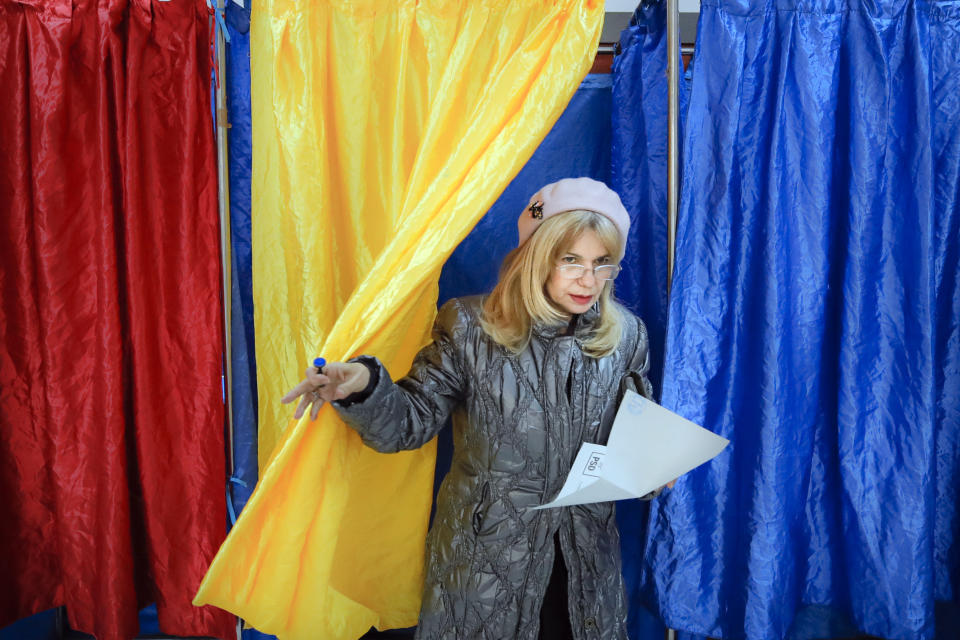 A woman exits a voting cabin with curtains in the colors of the country's national flag in Bucharest, Romania, Sunday, Nov. 24, 2019. Romanians are voting in a presidential runoff election in which incumbent Klaus Iohannis is vying for a second term, facing Social Democratic Party leader Viorica Dancila, a former prime minister, in Sunday's vote. (AP Photo/Vadim Ghirda)