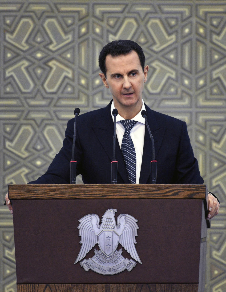 In this photo released by the Syrian official news agency SANA, Syrian President Bashar Assad speaks during a meeting with heads of local councils from all Syrian provinces, in Damascus, Syria, Sunday, Feb. 17, 2018. Assad said that only the Syrian army can protect groups in northern Syria. In a speech he appeared to be referring to U.S.-allied Kurdish groups, which fear a Turkish assault once American troops withdraw from northeastern Syria. (SANA via AP)