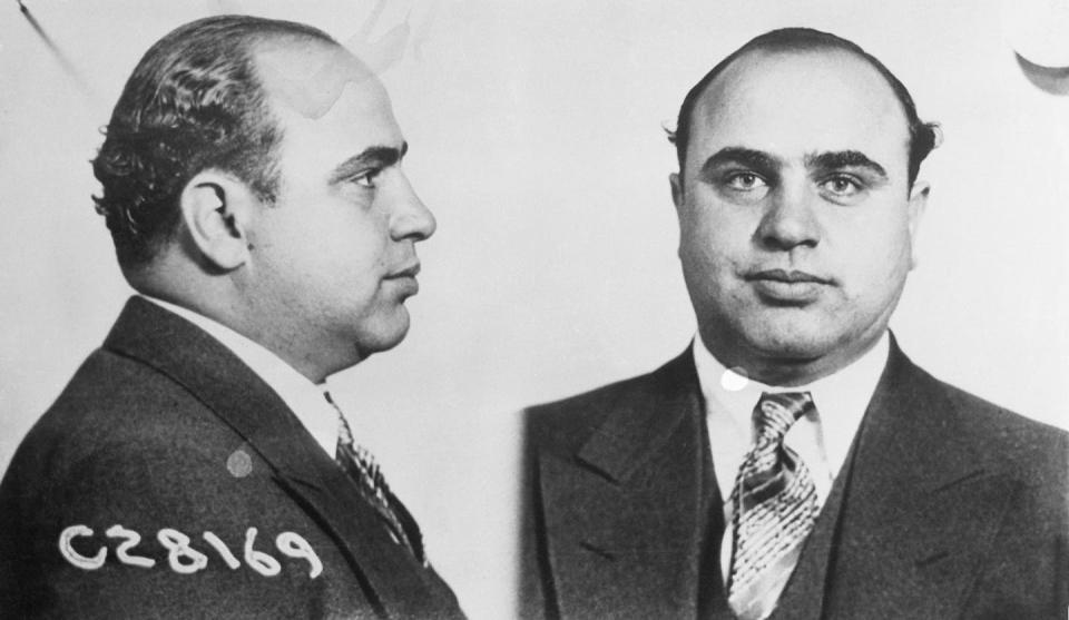 A balding man wearing a business suit and necktie poses for photographs.