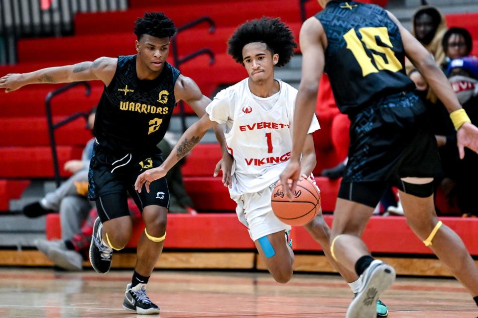 Everett's Christopher Robinson Jr., center, moves with the ball as Waverly's Deonte Roberts, left, defends during the fourth quarter on Tuesday, Jan. 18, 2022, at Everett High School in Lansing.