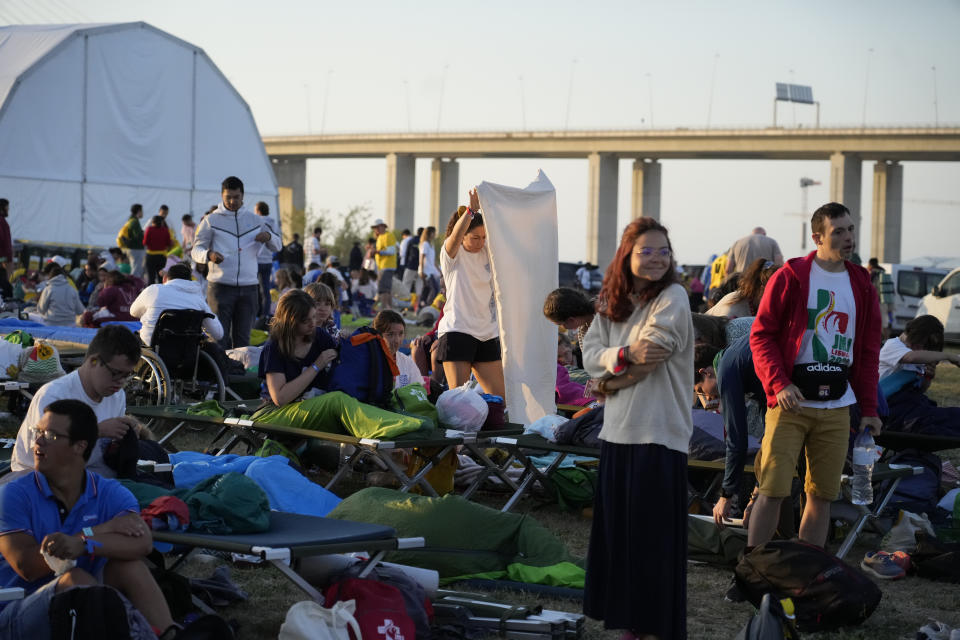 Pilgrims wake up after sleeping at the Parque Tejo in Lisbon where Pope Francis will preside over a mass celebrating the 37th World Youth Day, Sunday, Aug. 6, 2023. An estimated 1.5 million young people filled the parque on Saturday for Pope Francis' World Youth Day vigil, braving scorching heat to secure a spot for the evening prayer and to camp out overnight for his final farewell Mass on Sunday morning. (AP Photo/Gregorio Borgia)