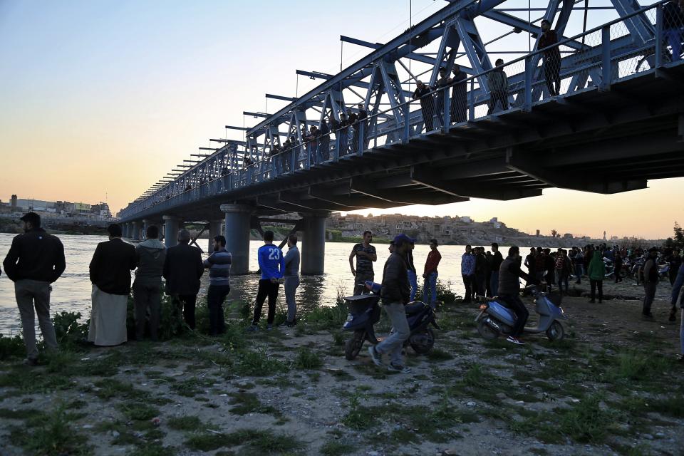 Personas y parientes de las víctimas esperan en la orilla del río Tigris en donde se hundió un ferry en Mosul, Irak, el jueves 21 de marzo de 2019. (AP Foto/Farid Abdulwahed)