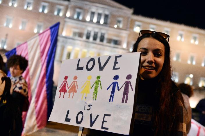 A woman holds a sign reading "Love is love" during a demonstration outside the Greek parliament in Athens on December 22, 2015 (AFP Photo/Louisa Gouliamaki)