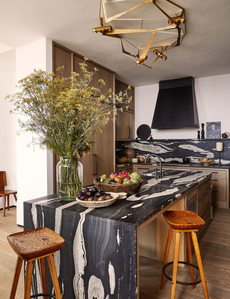 A Vincenzo de Cotiis Light fixture hangs above an island of honed Copacabana stone in the kitchen. Vintage stools; cabinetry hardware by the Nanz co.; Waterworks sink fittings; artwork from Dienst + Dotter.