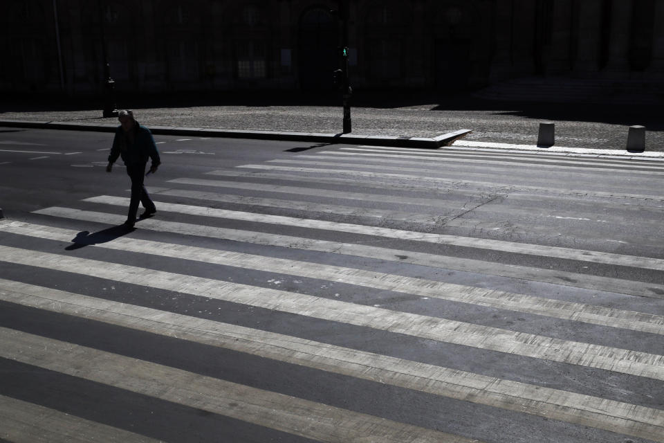 A man crosses an empty street during a nationwide confinement to counter the Covid-19, in Paris, Saturday, April 4, 2020. The new coronavirus causes mild or moderate symptoms for most people, but for some, especially older adults and people with existing health problems, it can cause more severe illness or death. (AP Photo/Christophe Ena)