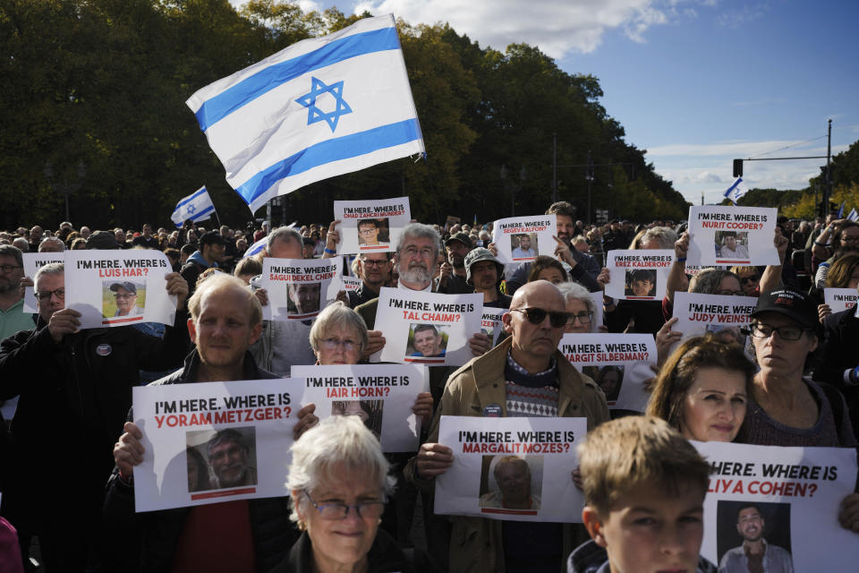 People wave Israeli flags and display posters with photos of people reported to be missing or held by Hamas as hostages, during a demonstration against antisemitism and to show solidarity with Israel in Berlin, Germany, Sunday, Oct. 22, 2023. (AP Photo/Markus Schreiber)