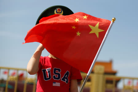 FILE PHOTO: A boy wearing an U.S. t-shirt waves a Chinese national flag in Tiananmen Square in Beijing, China May 7, 2019. REUTERS/Thomas Peter